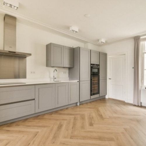 Renoveret køkken i Trekantsområdet med sildebensgulv og lyse køkkenelementer